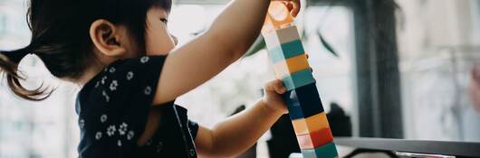 Creative little toddler girl playing with colorful building blocks at home.