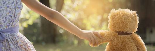 Young girl holding hands with a teddy bear