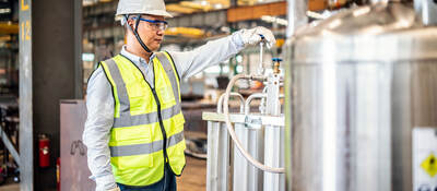 Worker operating a gas tank in a factory.  