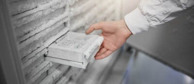 A scientist removing a sample from a laboratory freezer