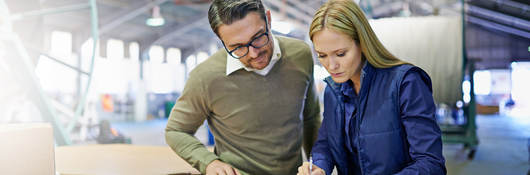 A Man and a woman look at something together in workplace