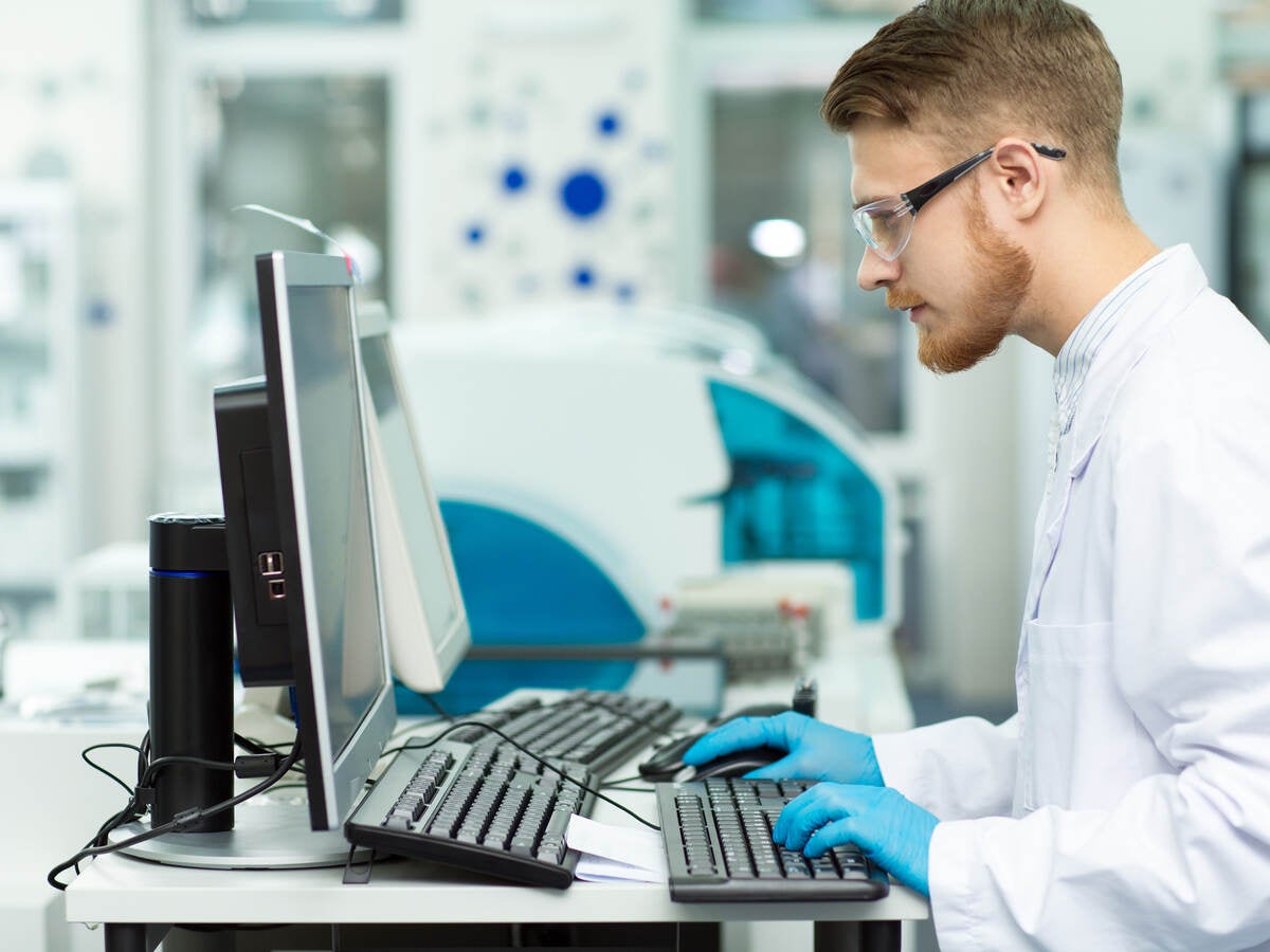 Two scientists in lab coats looking at a tablet screen.