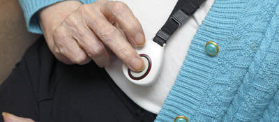 Elderly woman demonstrating call button worn on neck strap